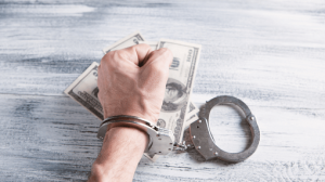 man with handcuffs ontop of dirty money